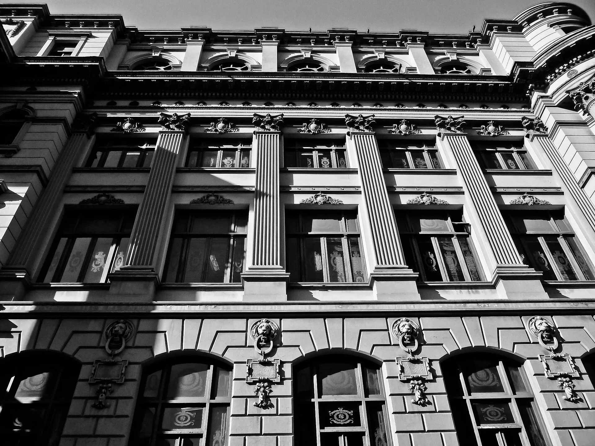 Fachada em preto e branco do prédio da Biblioteca Nacional, vista de baixo, com colunas, janelas altas e relevos de cabeças de leão