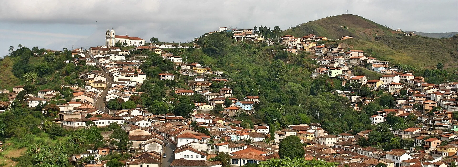Vista do centro histórico de Ouro Preto (MG), com casas de telhado vermelho e uma igreja branca no alto de uma colina