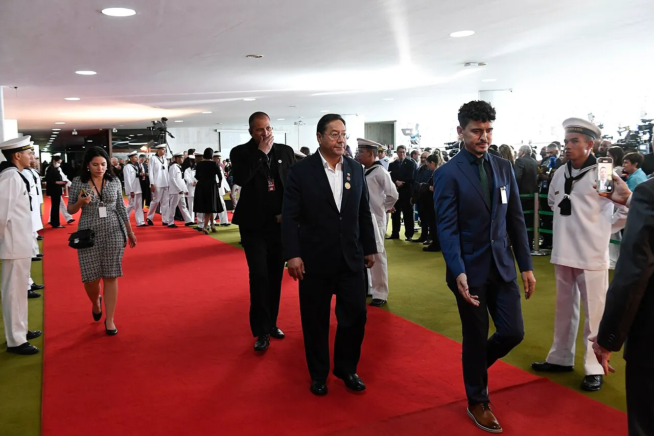 Convidados caminham por tapete vermelho no Congresso Nacional, entre marinheiros em uniforme branco e equipes de imprensa