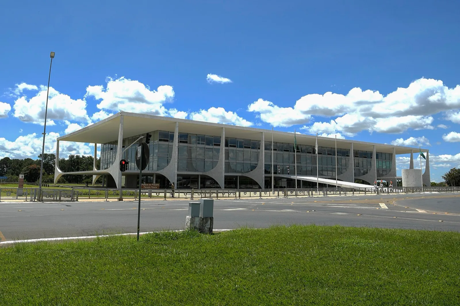 Fachada do Palácio do Planalto, com suas colunas curvas brancas, sob céu azul com nuvens